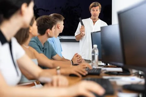 Students of computer courses sit in class near PC, watch to teacher and listen 写真素材