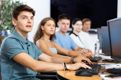 Students of computer courses sit in class near PC, watch to teacher and listen Stockfoto's
