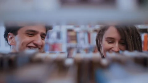 Students couple looking for books in a library Stockbeeldmateriaal 335129188
