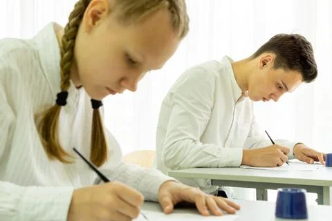 Students do the teacher's task, take exams sitting at a desk in a bright Stockfoto's