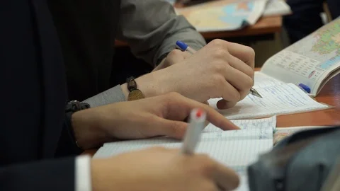 Students doing assignments in the classroom. They write with a pen in a notebook Stock Footage 100033695