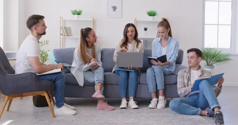 Students group sitting on sofa and studying preparing for test together making Stock Footage 344469347
