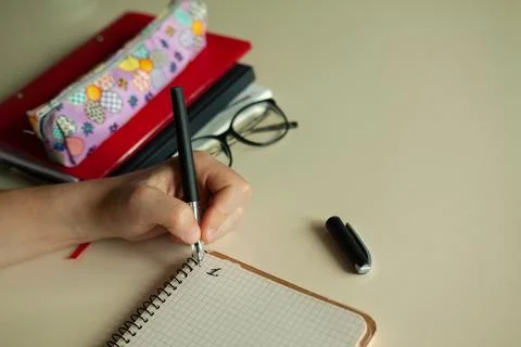 The student's hand writes with a pen in notebook Stock Photos