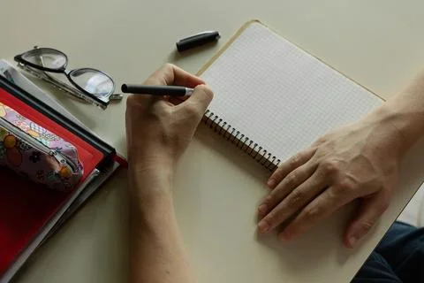 The student's hand writes with a pen in notebook Stock Photos