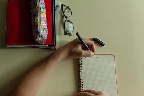 The student's hand writes with a pen in notebook Stock Photos