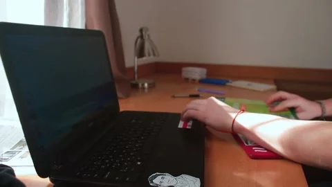 Student's hands leafing through magazine on table near computer. Video stock 149624477