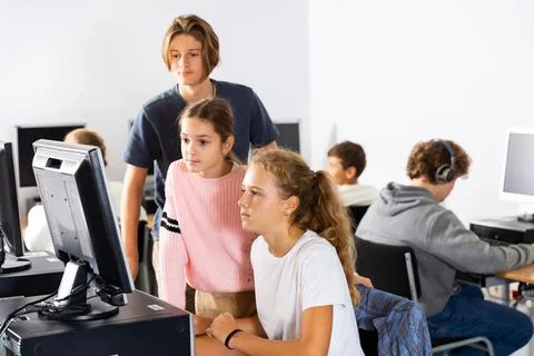 Students help each other solve problems on the computer in classroom Stock Photos