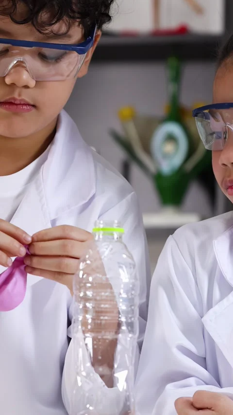 Students in Lab Coats Conducting Science Experiment with Balloon and Bottle Stock Footage 342686357