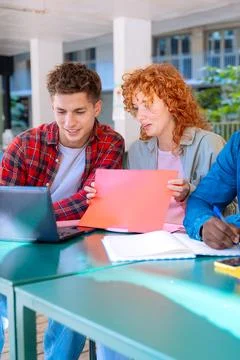 Students with laptops sit near the campus and communicate.Vertical Stock Photos