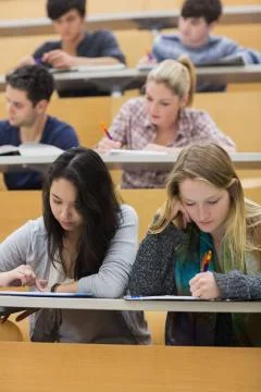 Students learning in a lecture hall with one girl using tablet pc Stock Photos