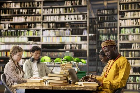 Students learning together at shared library table with open books Stock Photos