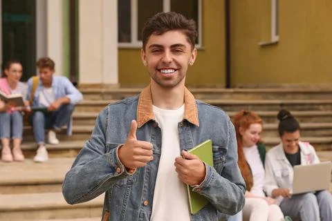 Students learning together on steps. Happy young man with notebook showing .. Foto stock