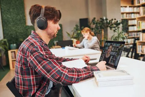 Students learning in university library. Young man having video class on la.. Foto stock