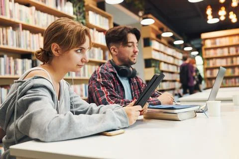 Students learning in university library. Young man preparing for test on la.. Stock Photos