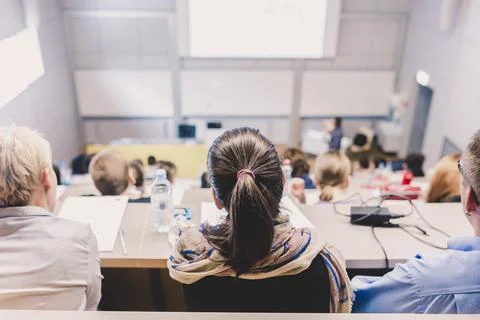 Students listening to lecture and making notes. Professor giving presentation in Stock Photos
