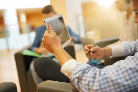 Students in lounge room connected with tablets Stock Photos