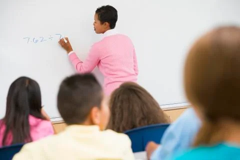 Students in math class with teacher writing on front board (selective focus) Stock Photos