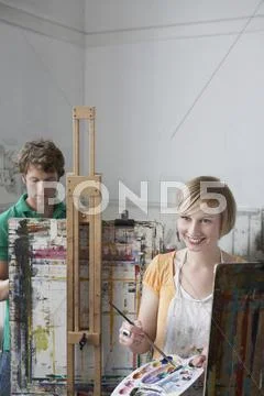 Students Painting At Easels In Art Class Stock Photos