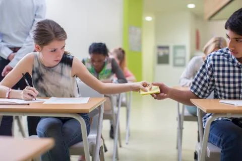 Students passing note between desks during GCSE examination Stock Photos