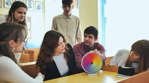 Students in physics class spin Newtons multicolored disk. Stock Photos