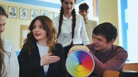 Students in physics class spin Newtons multicolored disk. Stock Photos