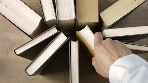 Students picking up a group of books from a library that are on the table Stock-Footage 132668346