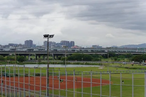 Students Practice Baseball on Field Beside Elevated Highway and Skyline Stock-Fotos