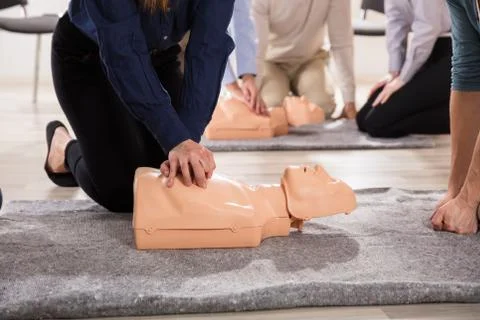 Students Practicing CPR Chest Compression On Dummy Foto stock