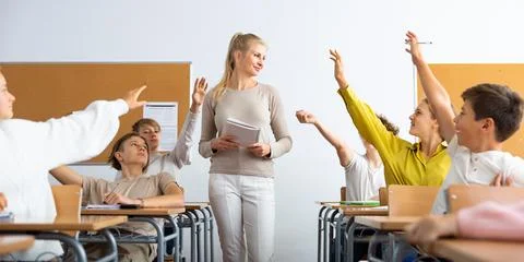 Students raise their hand to answer during lesson in class Stock Photos