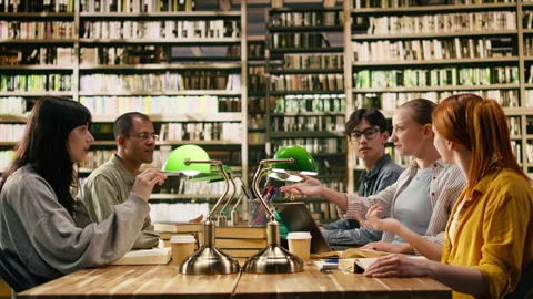 Students raising hands together in high five during library group study session Stock Footage 336358355