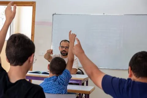Students raising their hands to answer the teacher question Stock Photos