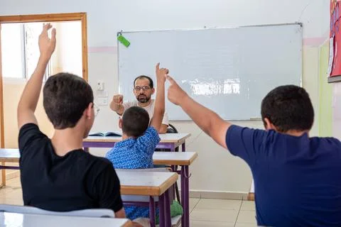 Students raising their hands to answer the teacher question Stock Photos