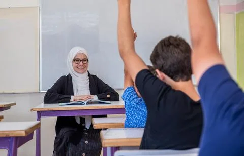 Students raising their hands to answer the teacher question Stock Photos