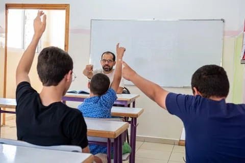 Students raising their hands to answer the teacher question Foto stock