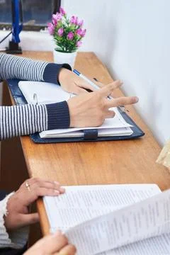 Students reading and taking notes together at wooden desk in cozy study setti Stock Photos