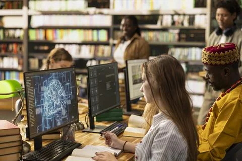 Students research AI brain visuals on desktop computer while reading books Stock Photos