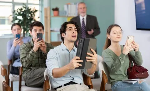 Students scanning QR code or taking photo, professor in background Foto stock