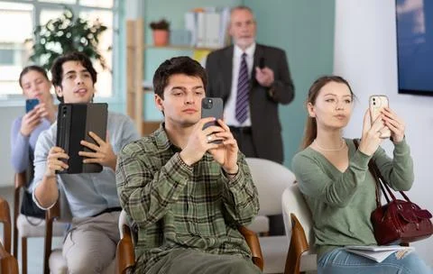Students scanning QR code or taking photo, professor in background Stockfoto's
