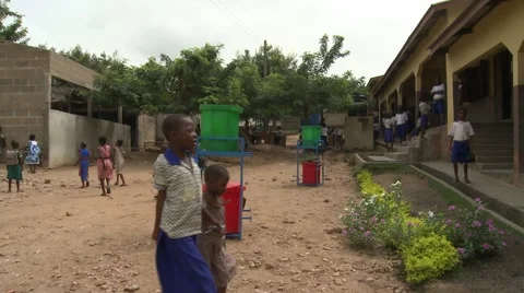 STUDENTS IN SCHOOL YARD WITH RED AND GREEN HAND WASHING STATIONS Stock Footage 60116040