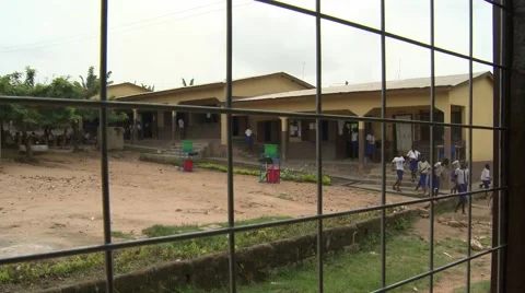 STUDENTS IN SCHOOL YARD SEEN THROUGH FENCE Stock Footage 60116023
