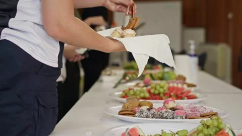 Students select cupcakes, biscuits and sweet treats from a refreshment table at Stock Footage 337546402
