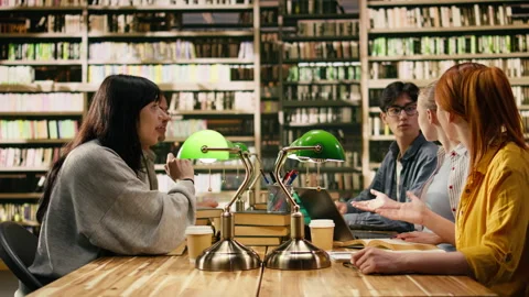 Students sharing high five in group study session at library table Stock Footage 336358354