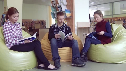 Students sitting and thumbing through the books in library Stock-Footage 73311235