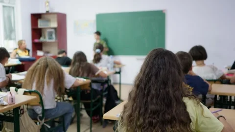 Students sitting at desks in a classroom during an art lesson with a teache.. Stock Footage 346181722