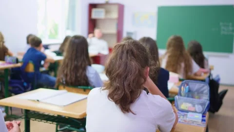 Students sitting at desks in a classroom raising hands to participate in a .. Stock Footage 345668641