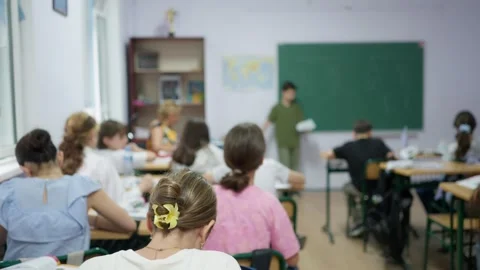 Students sitting at desks in a classroom while a classmate presents at the .. Stock Footage 346181772