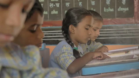 A students sitting reading from the text book in the classroom, Video stock 132609666