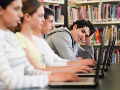 Students Sitting In Row Using Laptops In Library Stock Photos