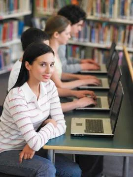 Students Sitting In Row Using Laptops In Library Stock Photos