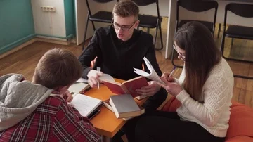 Students sitting at table with books and doing homework together Stock Footage 85906413
